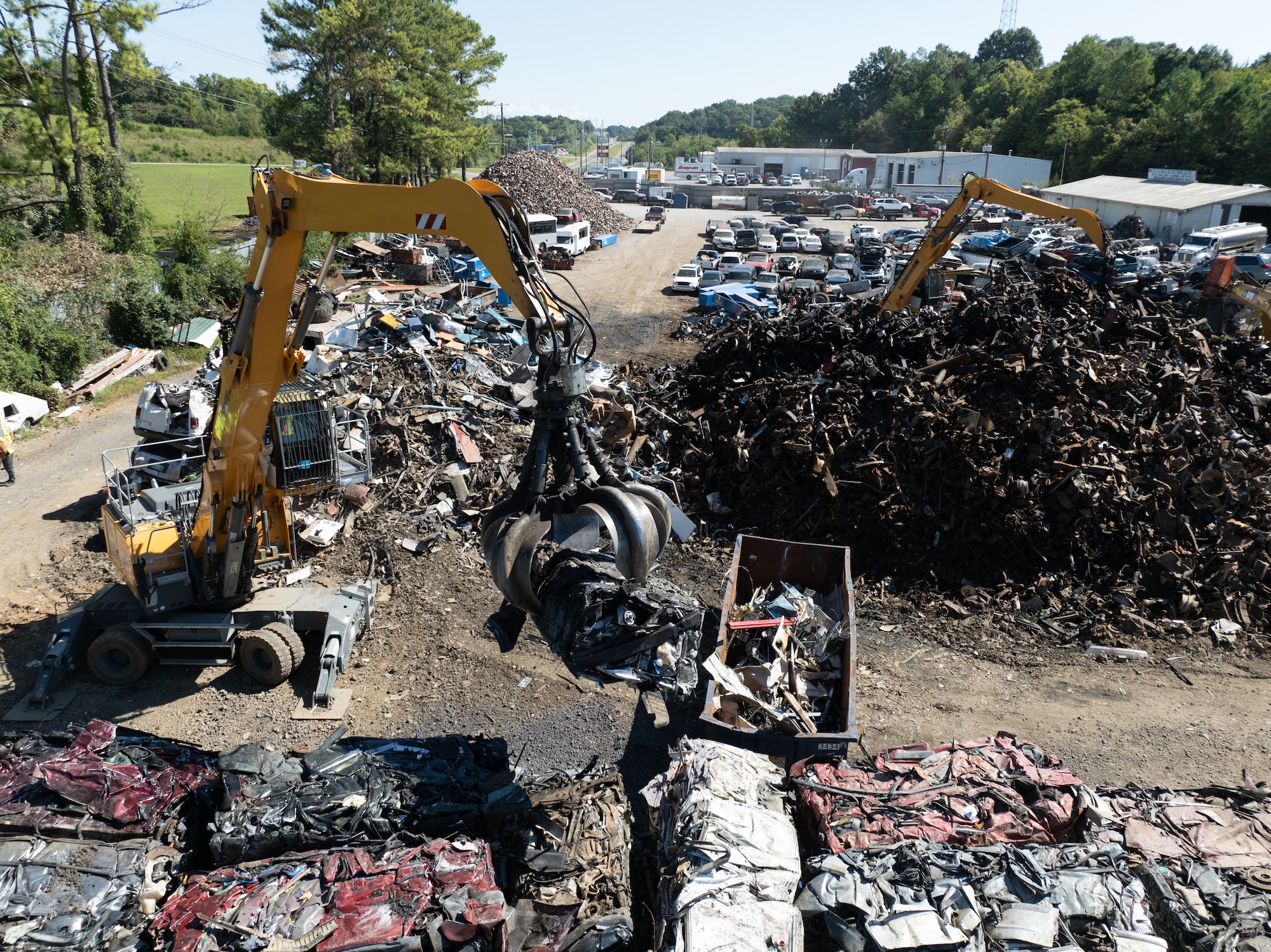 Large scrap piles and heavy machinery at TAS Recycling junk car removal site.
