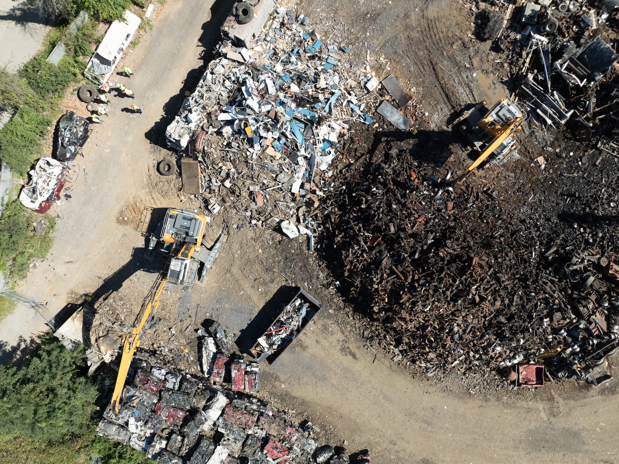 Overhead view of TAS Recycling’s metal recycling yard with excavators and compacted cars.