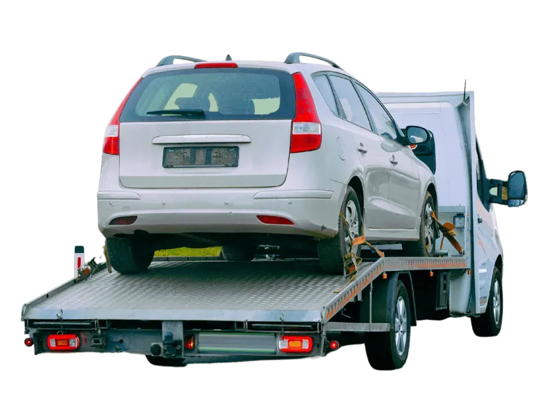 White car being hauled on a flatbed tow truck for recycling