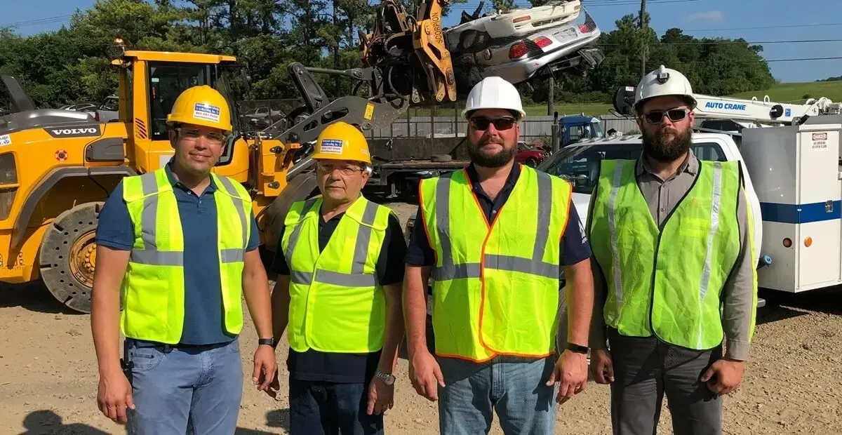 TAS Recycling crew wearing safety vests and hard hats at scrap yard